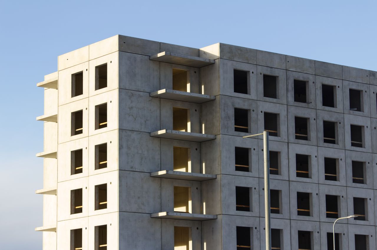 A multi-storey unfinished concrete building under blue skies during a sunny day.